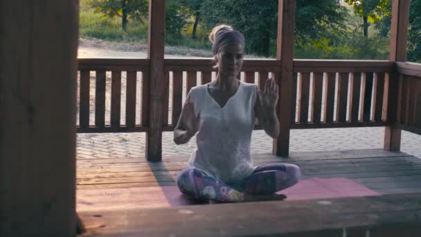 Приваблива жінка робить асан йоги на заході сонця — стокове відео