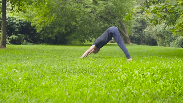 En man som gör yogaövningar i parken — Stockvideo