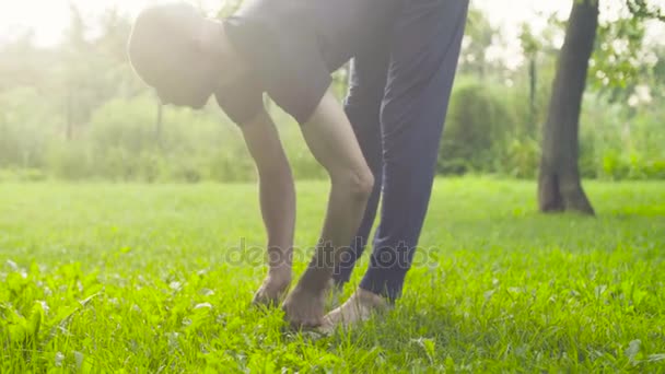 Een man doen yoga oefeningen in het park — Stockvideo