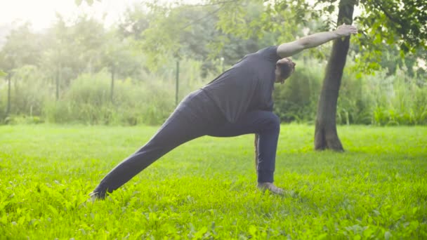 Un hombre haciendo ejercicios de yoga en el parque — Vídeo de stock