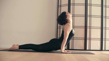 Genç bir kadın Yoga-asanas koridorda gerçekleştirme.