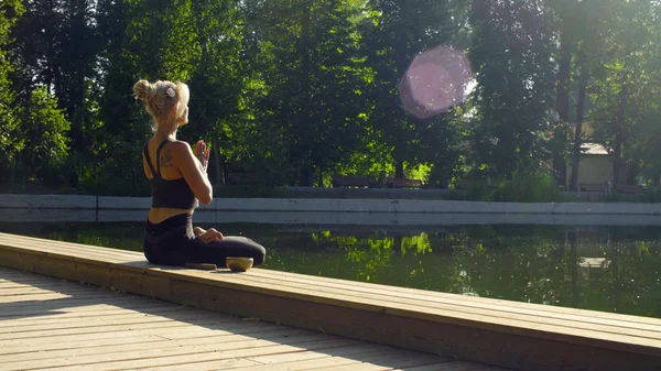 Fiatal nő meditál, a park a tó közelében — Stock Fotó