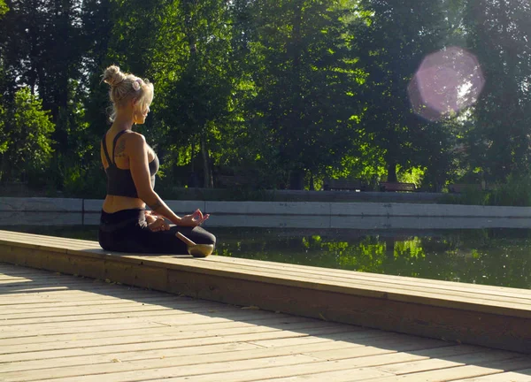 Fiatal nő meditál, a park a tó közelében — Stock Fotó