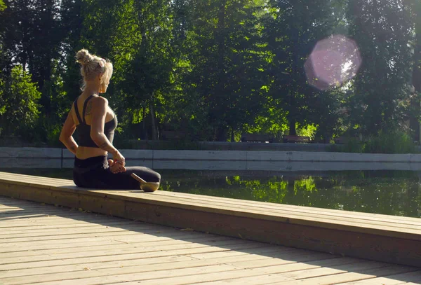 Fiatal nő meditál, a park a tó közelében — Stock Fotó