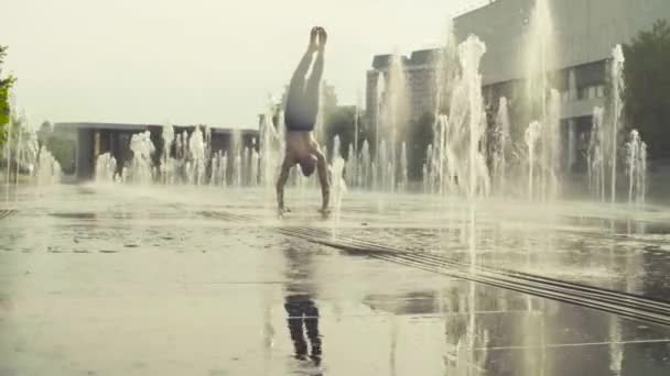 Strong man performing handstand in the fountain — Stock Video