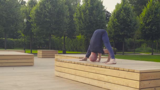 Um homem fazendo exercícios de ioga no parque — Vídeo de Stock