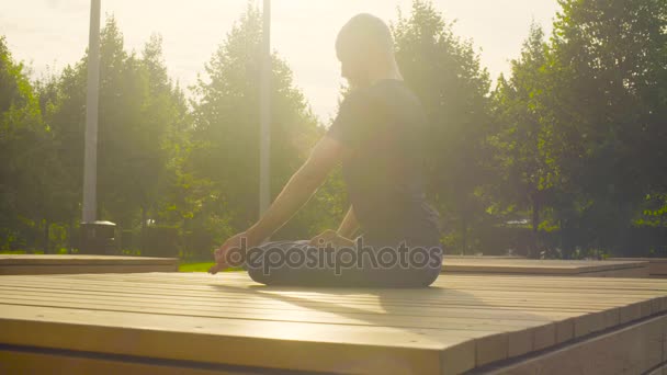 En man som gör yogaövningar i parken — Stockvideo