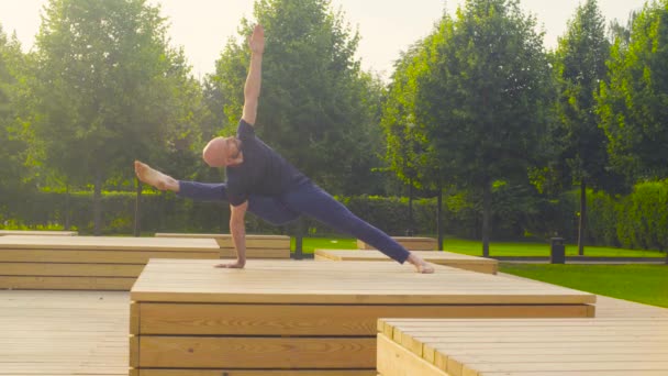 Een man doen yoga oefeningen in het park — Stockvideo