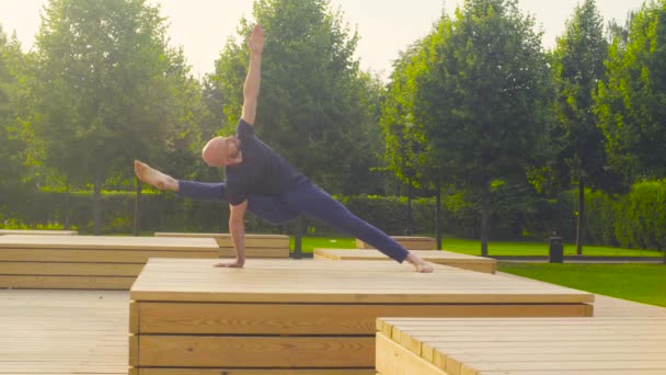 En man som gör yogaövningar i parken — Stockvideo