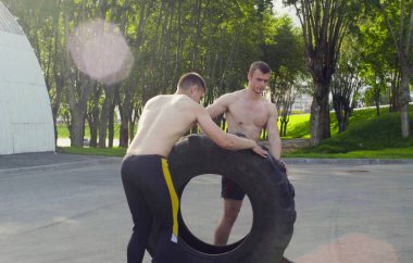 İki genç erkek egzersiz yapmak için bir tekerlek haddeleme