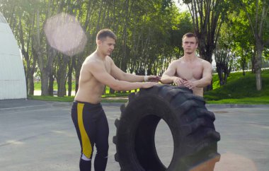 İki genç erkek egzersiz yapmak için bir tekerlek haddeleme