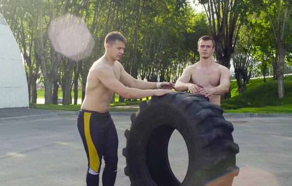 İki genç erkek egzersiz yapmak için bir tekerlek haddeleme