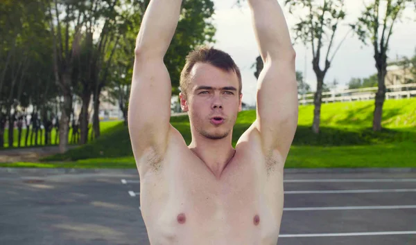 A young man is lifting dumbbells — Stock Photo, Image