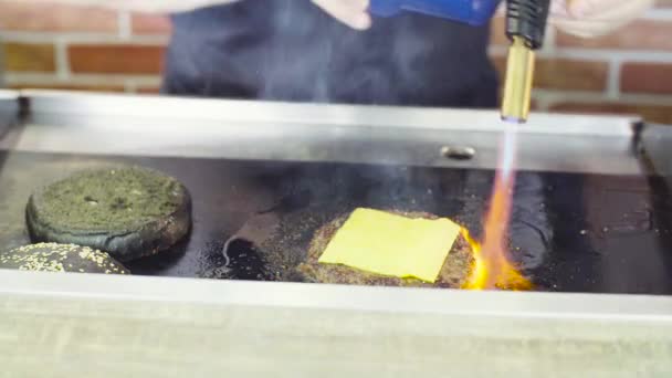 Manos de chef quemando una hamburguesa con una llama abierta — Vídeos de Stock