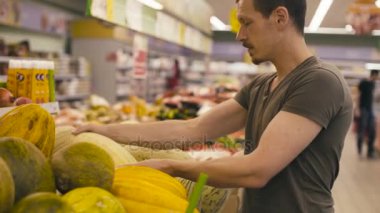 Bir adam bir süpermarkette kavun seçme