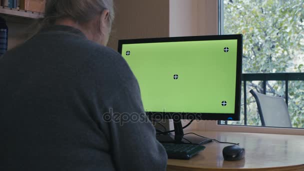 Mujer mayor escribiendo en una pantalla verde de la computadora — Vídeos de Stock