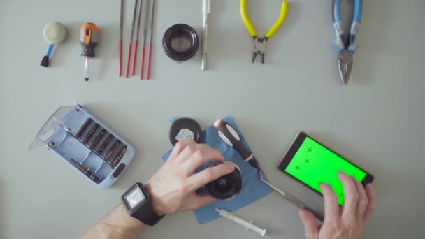 Male hands repair lens on grey table — Stock Video