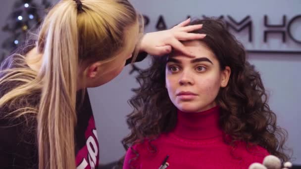 The makeup artist correcting the shape of eyebrow — Stock Video