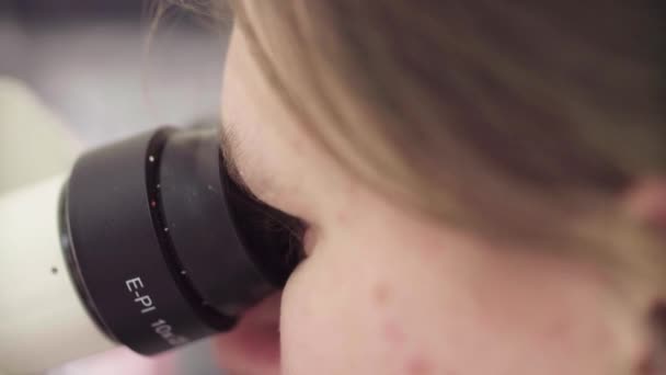 Scientist looking into eyepieces of a microscope — Stock Video