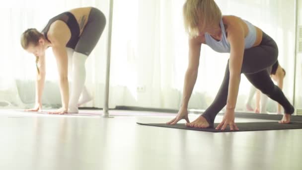 Dos mujeres haciendo ejercicios de estiramiento de yoga en estudio . — Vídeos de Stock