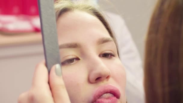 Vrouwelijke gezicht in de spiegel kijken naar haar lippen — Stockvideo