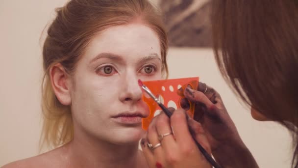 Maquillaje artista empezando a dibujar líneas en la cara — Vídeo de stock