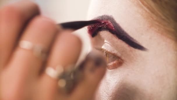 O artista de maquilagem que colore a sobrancelha vermelha de um modelo — Vídeo de Stock