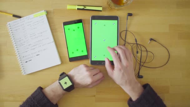 Три устройства с зелеными экранами на столе — стоковое видео