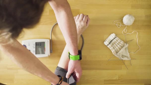 Homem jovem medindo a pressão arterial da mulher idosa — Vídeo de Stock