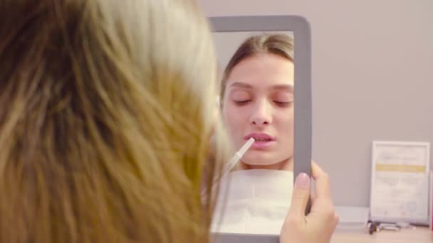 Visage féminin dans le miroir regardant ses lèvres — Video