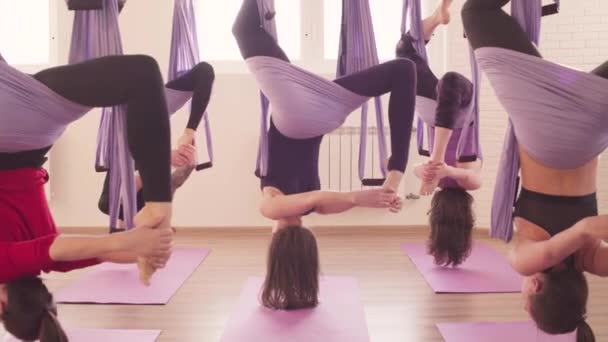 Grupo de personas haciendo asanas aéreas de yoga en el gimnasio — Vídeo de stock