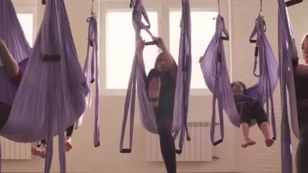 Group of people doing aerial yoga asanas in gym — Stock Video