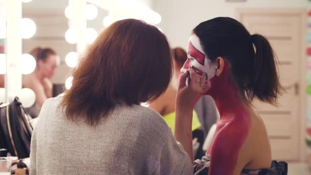 Maquillaje artista pintura con color rojo en la cara — Vídeo de stock