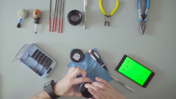 Hands with screwdriver and tweezers repair lens — Stock Video