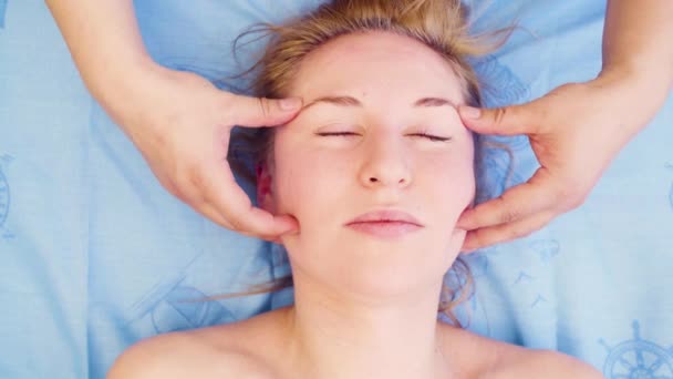 Händerna på terapeuten gör massage av kvinnliga ansikte — Stockvideo