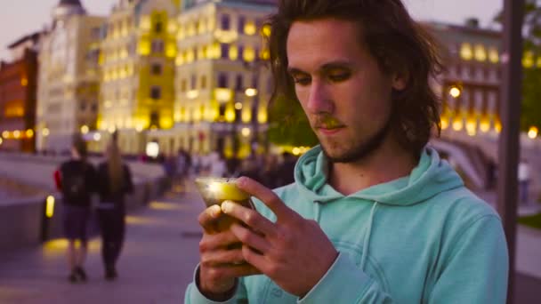 Человек с мобильным телефоном против вечернего города — стоковое видео