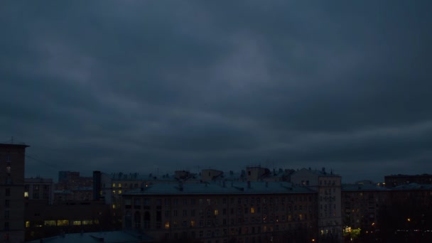 街の上に暗い曇りの空 鳥が空を飛んでいる 家の窓には光が灯っている 夜の時間 時間の経過 空の背景 — ストック動画