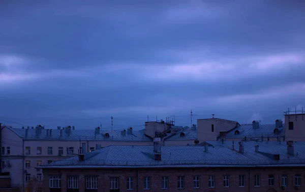 Donkere bewolkte lucht boven stadsgebouwen — Stockfoto