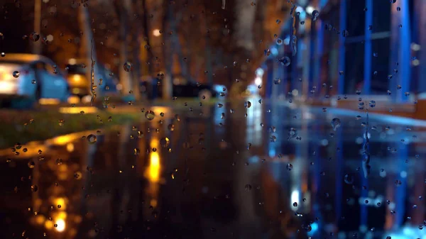 Vetro di finestra in giorno piovoso. Semaforo notturno di Bokeh . — Foto Stock