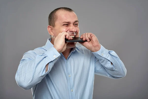Naštvaný obchodní muž kousání jeho mobil — Stock fotografie