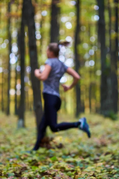 Женщина, бегущая в осеннем лесу — стоковое фото