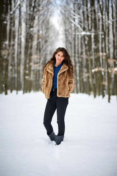 Νεαρή γυναίκα που είναι εξωτερική στο χιονισμένο πάρκο — Φωτογραφία Αρχείου