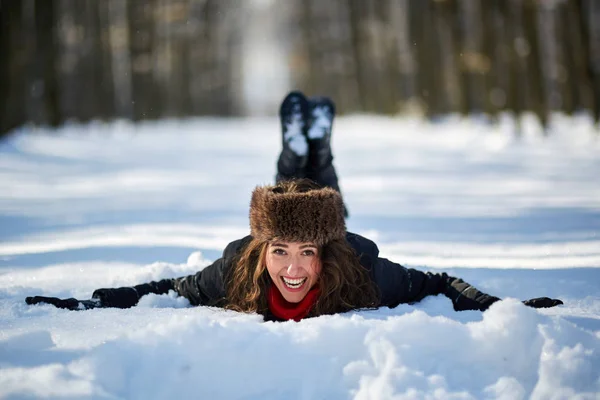 Ung kvinna som ligger i snön — Stockfoto