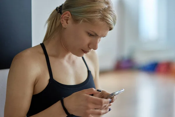 Тренер по фитнесу проверяет ее встречи по мобильному телефону — стоковое фото