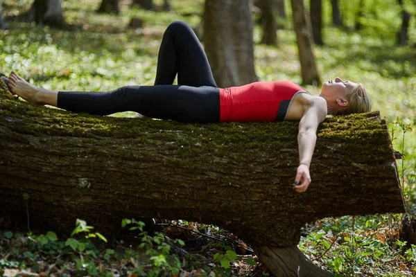 Молода жінка лежить на стовбурі дерева — стокове фото