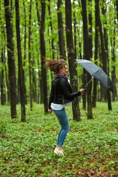 Frau mit Regenschirm springt in Park — Stockfoto