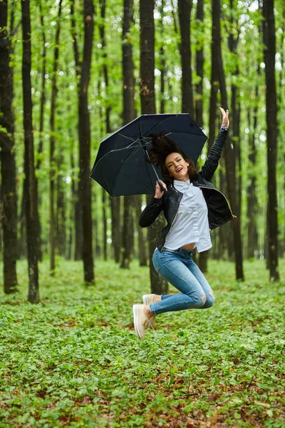Woman with umbrella jumping in park — Stock Photo, Image