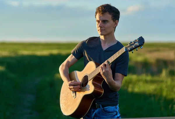 Jongen gitaarspelen op tarweveld — Stockfoto