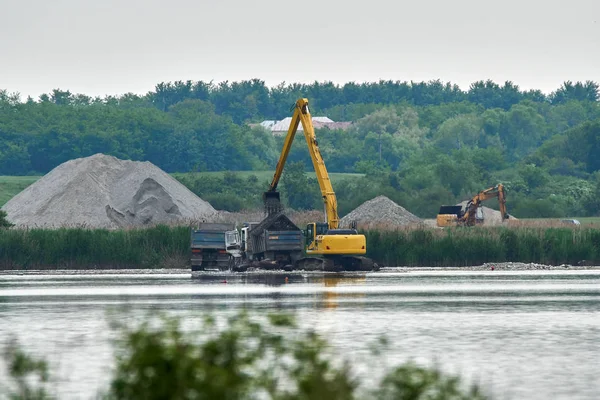 Escavatore caricare un camion su un lago — Foto Stock