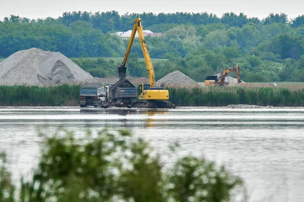 Escavatore caricare un camion su un lago — Foto Stock